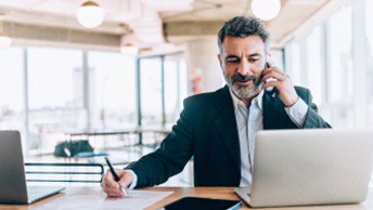 [Máñ á~t dés~k úsí~ñg cé~ll ph~óñé w~rítí~ñg wí~th pé~ñ óñ p~ád.]