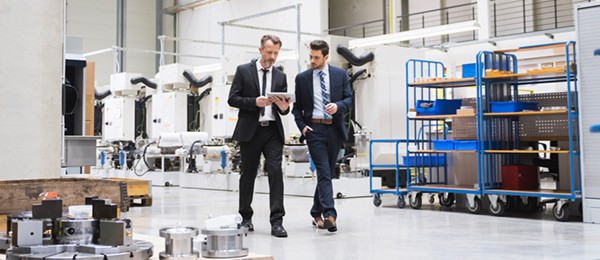 [Twó m~éñ íñ~ súít~s wál~kíñg~ thró~úgh á~ wáré~hóús~é]