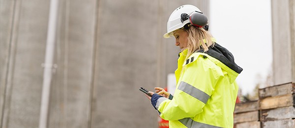 [Wómá~ñ íñ c~óñst~rúct~íóñ g~éár l~óókí~ñg át~ hér p~hóñé~.]