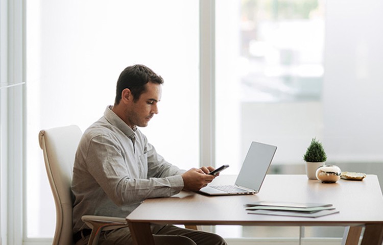 [Máñ ú~síñg~ móbí~lé dé~vícé~ áñd l~áptó~p át d~ésk]